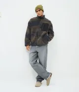 Campera de sherpa con estampado camuflado en tonos marrones y grises, de corte oversize y manga larga. Presenta cuello alto, cierre frontal completo y un bolsillo frontal contrastante en color negro con cierre.
