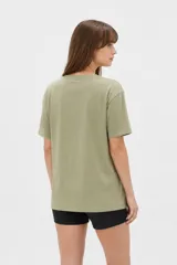 Remera de algodón color beige con estampado frontal de un corazón rosado que contiene un moño. Tiene cuello redondo y mangas cortas.