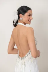 Vestido largo de seda natural color blanco, con escote halter tipo Marilyn y espalda descubierta. Presenta un elaborado bordado a mano con pedrería en la parte superior y caída fluida.