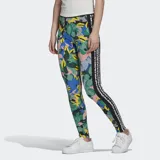 Calza larga Adidas con estampado floral multicolor y las tres líneas clásicas de la marca en los laterales.