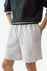Short de lino y viscosa, color blanco con rayas verticales delgadas, corte relajado, cintura elástica con cordón de ajuste y bolsillos laterales.