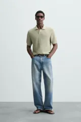 Polo de manga corta color verde azulado oscuro, confeccionado en tejido de punto con textura. Presenta cuello solapa y cierre frontal de botonadura.