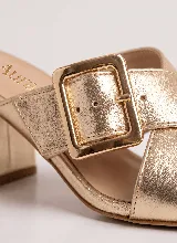 Sandalia de taco ancho color dorado, confeccionada en cuero vacuno, con diseño de tiras cruzadas y hebilla metálica decorativa.