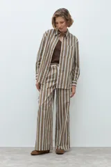 Pantalón de corte recto y tiro medio, con diseño de rayas verticales en tonos marrón, blanco y azul. Cuenta con cierre frontal y bolsillos laterales.