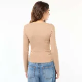 Remera color beige de corte cropped, con cuello redondo y mangas largas. Presenta un frunce lateral que genera un efecto arrugado.