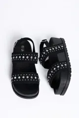 Sandalia chunky de plataforma color negro, con diseño de doble tira ancha decorada con tachas metálicas cónicas y pulsera ajustable al tobillo con hebilla.