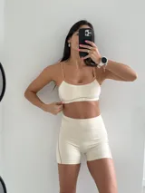 Conjunto deportivo compuesto por un top y un short de tiro alto en color beige con detalles en color tostado. El top presenta breteles finos y el short tiene un diseño ajustado con costuras laterales visibles.