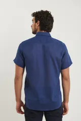 Camisa azul de manga corta, con cuello abotonado y bolsillo en el pecho.