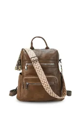 Mochila de símil cuero color marrón con apertura superior y tres bolsillos frontales con cierres metálicos. Cuenta con bolsillos laterales y una correa de galón con diseño geométrico, regulable y extraíble, que permite su uso como bandolera.