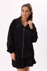 Conjunto deportivo compuesto por un buzo con cierre frontal y una falda corta, confeccionados en algodón liviano. El buzo presenta cuello alto, mangas largas con puños elásticos y un diseño holgado.