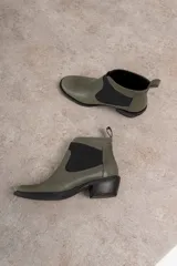 Botín negro de cuero con elásticos laterales, taco bajo y tirador trasero.