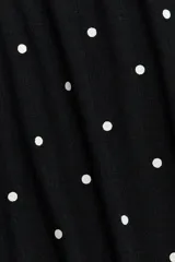 Pantalón de pijama confeccionado en punto pointelle suave, color negro con estampado de pequeños lunares blancos. Cuenta con perneras levemente acampanadas, cintura elástica con ribete de volados y cordón ajustable.