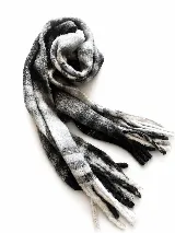 Bufanda tejida de textura suave, con diseño a cuadros en tonos grises, blancos y negros, terminada con flecos en los extremos.