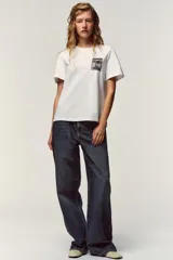 Camiseta blanca de manga corta y cuello redondo, con aplicación de organza y texto negro a contraste en el pecho.