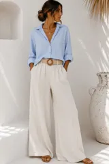Pantalón palazzo de lino color beige, de corte ancho y tiro alto, con bolsillos laterales y presillas para cinturón.