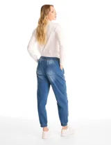 Pantalón tipo jogger de denim azul con efecto lavado. Presenta cintura elástica con cordón ajustable, bolsillos laterales y traseros, y puños elásticos en los tobillos.