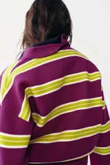 Jersey de punto con diseño de rayas horizontales en colores violeta y verde lima, cuello polo con escote en pico y manga larga con puños ajustados.