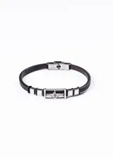 Pulsera de cuero negro con apliques de acero inoxidable plateado. En el centro presenta un dije rectangular con un águila grabada.