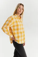 Camisa de franela a cuadros amarillos y blancos, de corte recto y manga larga.