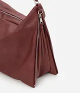 Bolso hobo grande de poliuretano color bordó, de diseño desestructurado con asas dobles y cierres laterales ajustables con tiradores. Cuenta con cierre superior y herrajes metálicos plateados.