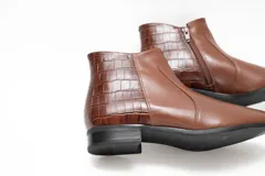 Botineta de cuero color chocolate con diseño clásico y talón con textura efecto cocodrilo. Cuenta con suela baja y cierre lateral interno.