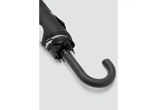Paraguas plegable de color negro con estampado de lunares blancos grandes, cuenta con mango curvo ergonómico.