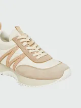 Zapatillas Moncler modelo Pacey, confeccionadas en una combinación de cuero y gamuza en tonos crema y beige. Presentan un diseño de paneles con cordones al tono y suela de goma.