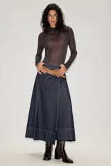 Falda midi de denim azul oscuro con costuras a la vista en contraste. Presenta un diseño de corte recto con paneles verticales y un cinturón de gamuza en tono tostado con hebilla metálica.