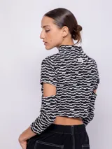 Top corto de tejido con estampado geométrico retro en tonos rosa, gris y negro. Es de manga larga con cut-out en los codos y cuello alto.