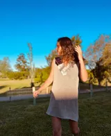 Vestido corto tejido en hilado de algodón color beige, con cuello en V y apliques de cuero en tonos dorados y marrones.