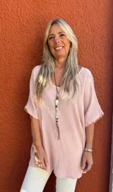 Blusa de textura arrugada en color rosado, con cuello redondo, mangas cortas amplias y corte holgado.