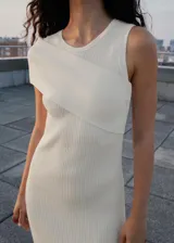 Vestido largo de punto acanalado en color blanco, con diseño entallado y cuello redondo. Presenta un estilo asimétrico en la parte superior con una manga corta y un hombro descubierto.