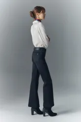 Pantalón de jean negro de tiro medio, corte ajustado en la cintura y muslos, y acampanado desde la rodilla hasta el ruedo. Confeccionado en tejido confort con elastano, cierre y botón.