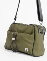 Bandolera color verde militar, confeccionada en material waterproof. Cuenta con doble cierre en el compartimento principal, un bolsillo frontal con cierre y cordón ajustable con stopper, y un bolsillo trasero con cierre. Incluye correa larga regulable de color negro.