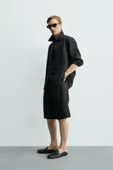 Bermuda relaxed fit de color negro, confeccionada en tejido fluido con viscosa y modal. Presenta cintura elástica ajustable con cordón, pliegues en el delantero, bolsillos frontales y bolsillos traseros de vivo.