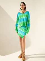 Minifalda de tejido de red teñida con técnica batik en tonos verde y celeste, con flecos y canutillos en un lateral.
