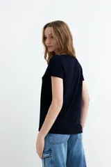 Remera negra de manga corta, con escote en V adornado con detalle de broderie.