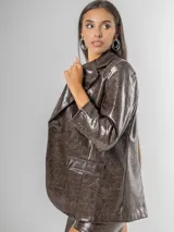 Blazer de mujer color marrón chocolate, confeccionado en ecocuero texturizado con acabado acharolado. Es forrado y presenta un corte estructurado con solapas y bolsillos frontales.