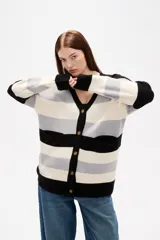 Saco de punto con diseño de rayas horizontales en negro, gris y blanco. Presenta cuello en V, cierre frontal con botones y bolsillos laterales.