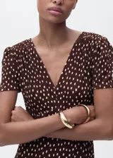 Vestido midi de corte recto con estampado de lunares, cuello en pico y mangas cortas. Presenta cierre de cremallera lateral y abertura en el bajo.