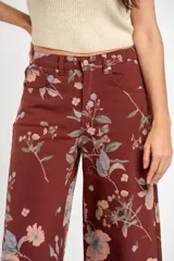 Jean de corte wide leg con tiro medio, confeccionado en algodón peinado. Presenta un diseño estampado con motivos florales sobre una base de color bordó.