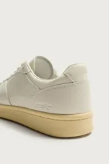 Zapatillas de piel estilo retro, color blanco crudo, con suela de goma con volumen en tono tostado y cierre de cordones.