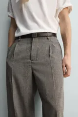 Pantalón de corte relajado con diseño de cuadros, confeccionado en tejido con lana. Presenta cintura con pliegues frontales, bolsillos laterales y bolsillos traseros de vivo, con cierre frontal de cremallera y gancho metálico oculto.