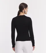 Blusa de punto ajustada color negro, con cuello polo y escote pronunciado en V. Presenta un tejido acanalado vertical en el torso y mangas largas.