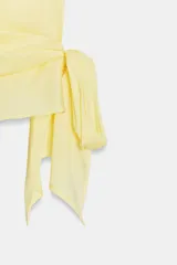 Top de popelín color amarillo claro, sin mangas, con hombreras marcadas, cuello alto y drapeado frontal con lazada lateral en la cintura.