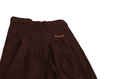 Pantalón de vestir azul marino, de corte recto, con bolsillos laterales y traseros. Se ajusta a la cintura con cinturón de cuero marrón. Tiene un cierre con botones en el tobillo.