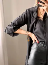Camisa negra de tejido suave tipo seda, con manga tres cuartos y volados irregulares en mangas y ruedo.