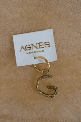 Aro tipo argolla con dije colgante en forma de letra, fabricado en bronce. Se vende por unidad.