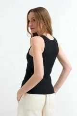 Top tejido en canalé color blanco, de corte ajustado, sin mangas y con escote redondo pronunciado.