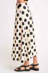 Falda midi color crudo con estampado de lunares negros, corte evasé y cintura alta.